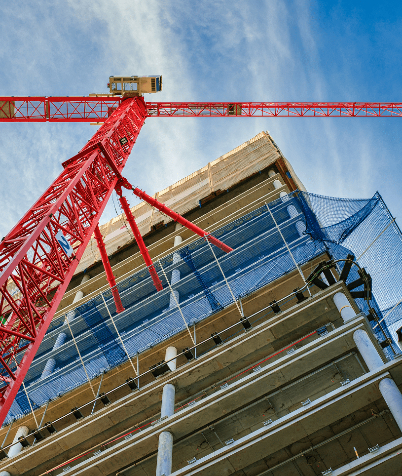 High-rise building with red crane nearby.